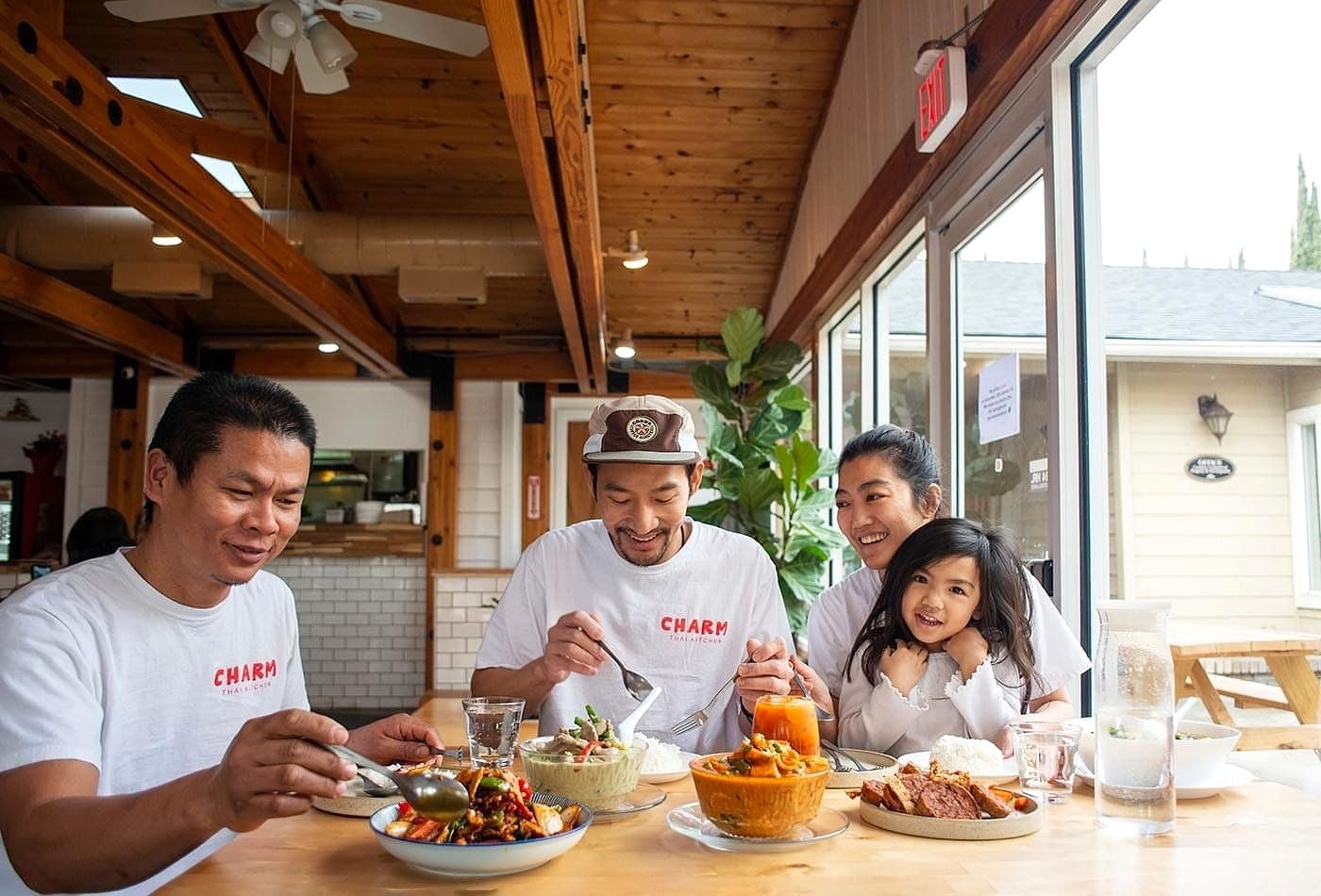 Staff smiling together at a table full of Thai dishes in the restaurant